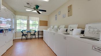 a laundry room with washers and dryers and a table with chairs  at Arbors Of Cleburne, Texas
